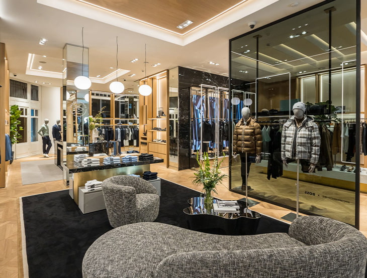HUGO-BOSS store with shelves, products for men and a sofa, styled in a warm, golden-bronze tone (photo)